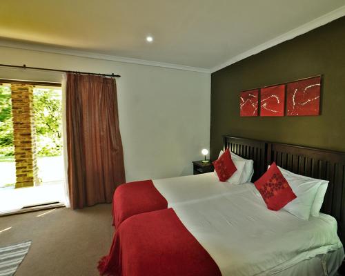 a bedroom with a bed with red pillows and a window at Chillifields Guesthouse in Hillcrest
