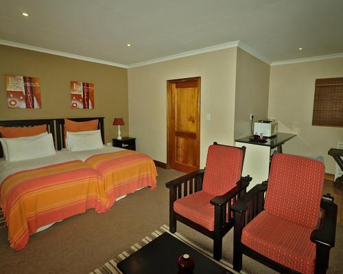 a hotel room with a bed and two chairs at Chillifields Guesthouse in Hillcrest