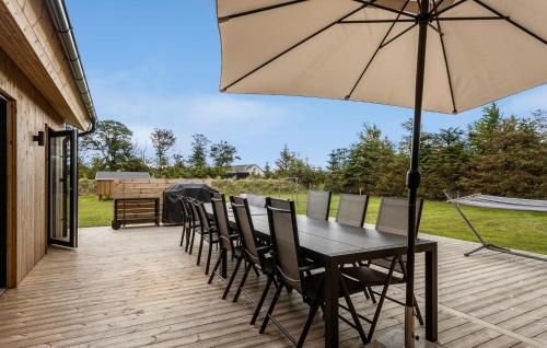 a table and chairs with an umbrella on a deck at Amazing Home In Sæby With Sauna in Sæby