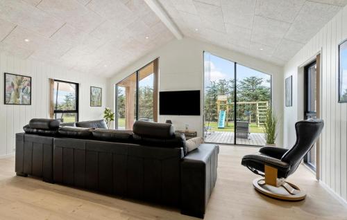 a living room with a black leather couch and a television at Amazing Home In Sæby With Sauna in Sæby