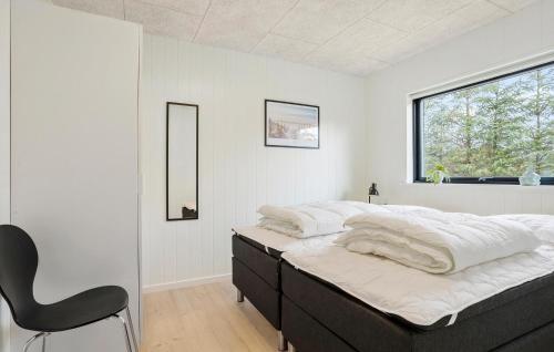 a bedroom with a bed with a chair and a window at Amazing Home In Sæby With Sauna in Sæby