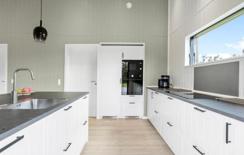 a kitchen with white cabinets and a sink and a window at Amazing Home In Sæby With Sauna in Sæby
