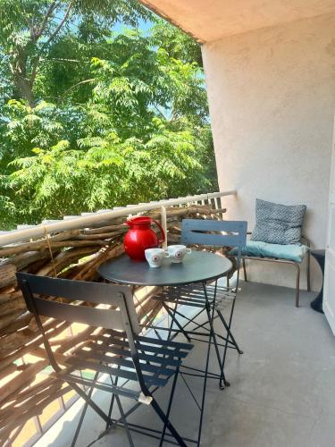 d'une table et de chaises sur un balcon avec vue sur les arbres. dans l'établissement MAISON CABROL, à Carqueiranne