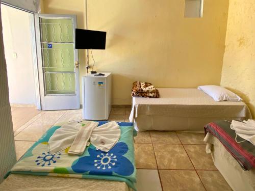 a small room with two beds and a refrigerator at Pousada Encantos da Serra Macacos in Macacos