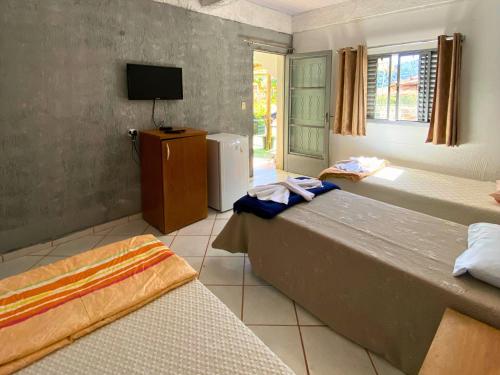 a bedroom with two beds and a tv in it at Pousada Encantos da Serra Macacos in Macacos