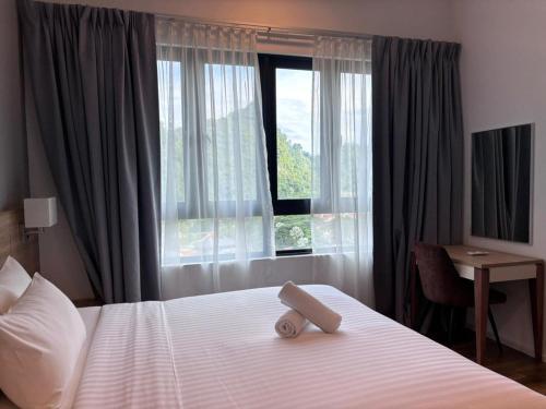 a bed in a hotel room with a large window at Theme Park Ipoh - Onsen Premier Suites By MICASA GROUP in Ipoh