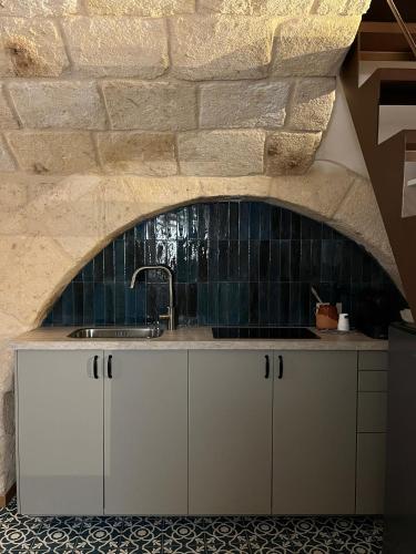 a kitchen with white cabinets and a stone wall at Dimora Noblac in Monopoli