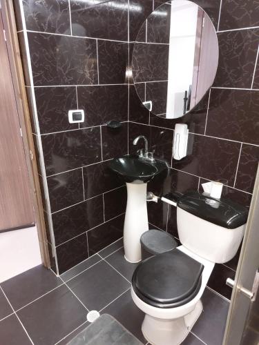 a black tiled bathroom with a toilet and a sink at Hospedaje Marina - 302 in Ibagué