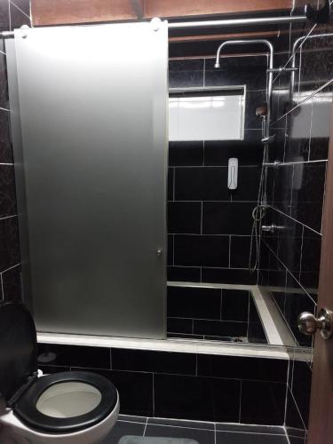 a bathroom with a toilet and black tile walls at Hospedaje Marina - 302 in Ibagué