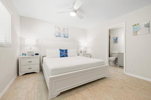 a white bedroom with a bed and a bathroom at Bianco Sands By Beachside Management in Siesta Key
