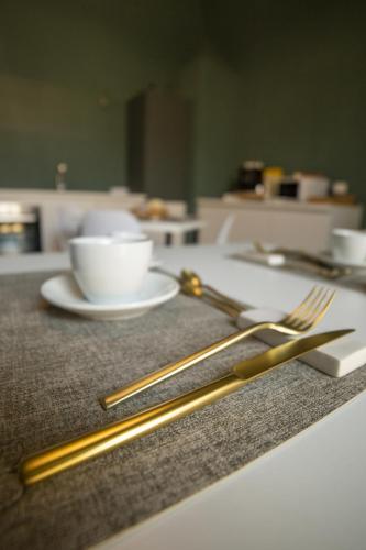 a table with two gold chopsticks and a cup of coffee at Maison Le Blanc Luxury B&B in Giovinazzo