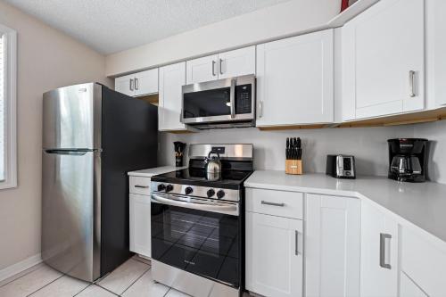 a kitchen with white cabinets and a stainless steel refrigerator at Bianco Sands By Beachside Management in Siesta Key