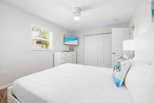 a white bedroom with a white bed and a window at Bianco Sands By Beachside Management in Siesta Key