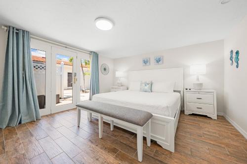 a white bedroom with a bed and a window at Bianco Sands By Beachside Management in Siesta Key