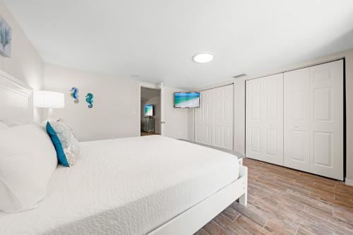 a white bedroom with a white bed and a tv at Bianco Sands By Beachside Management in Siesta Key