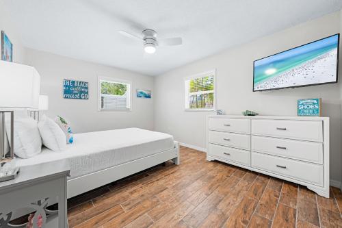 a white bedroom with a bed and a dresser at Bianco Sands By Beachside Management in Siesta Key