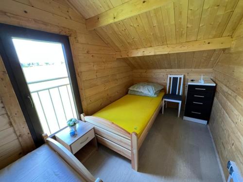 een kleine slaapkamer met een geel bed in een houten hut bij Domek nad jeziorem Jan, Giże in Giże