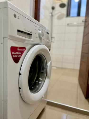 a white washing machine sitting in a bathroom at Tai Africa Guest Rooms in Arusha