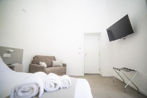 a living room with a bed and a chair with towels at Maison Le Blanc Luxury B&B in Giovinazzo