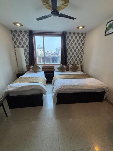 two beds in a room with a window at Hotel Shilva Inn in Varanasi