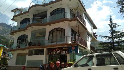 a white car parked in front of a building at Hotel Holiday Hill Mcleodganj-Near to Dalai Lama Temple & Mall Road in Dharmsala