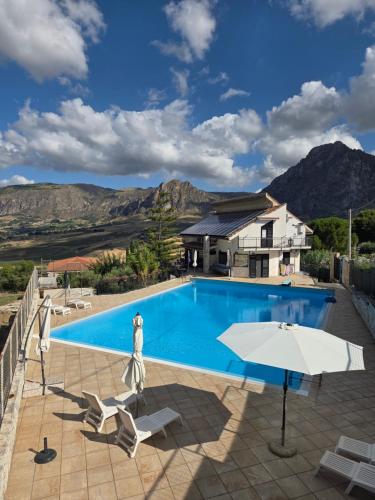 a swimming pool with two chairs and an umbrella at Kairos B&B in San Giuseppe Jato
