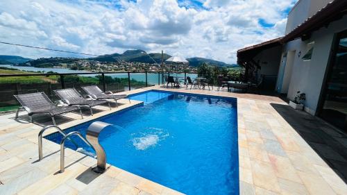 a swimming pool with chairs and a view of the water at Pousada Capitólio in Capitólio