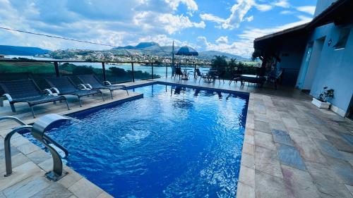 a swimming pool with chairs and a view of the mountains at Pousada Capitólio in Capitólio