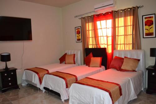 a bedroom with two beds and a flat screen tv at Negril Sky Blue Resorts LTD in Negril