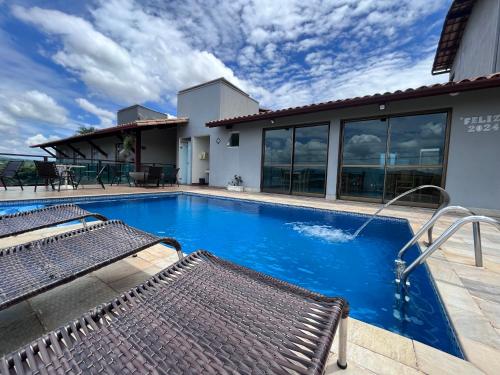 a swimming pool with a bench in front of a house at Pousada Capitólio in Capitólio