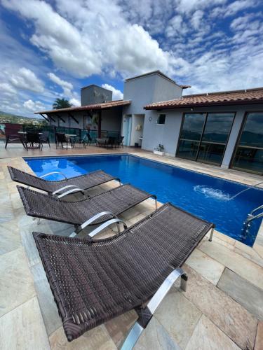 a swimming pool with two lounge chairs next to a house at Pousada Capitólio in Capitólio