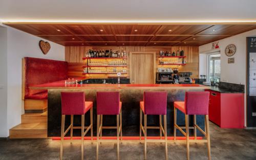 a bar with purple and red chairs in a restaurant at Hotel Garni Herz in Tirolo