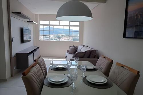 a dining room with a table and chairs and a couch at Cobertura magnifica in São Roque