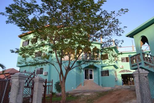 a blue and green house with a tree in front at Negril Sky Blue Resorts LTD in Negril