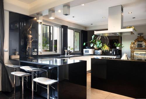 a kitchen with a large black counter and stools at Appartement confortable, central 200m2 in Levallois-Perret