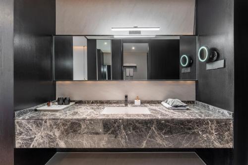 a bathroom with a sink and a large mirror at HeSu Hidden Art Hotel & Suites - Near Bell Tower & Ideal Location-Spacious rooms featuring King or Double Queen beds -Exclusive Two&Three-Bedroom Suites with Expansive Living Rooms for Group Gathering-Kitty Cuddles & Coffee Gift -Seamless Journey Planning in Xi'an