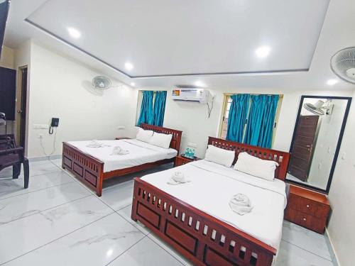 a hotel room with two beds and a mirror at FLORA INN Gokarna in Gokarna