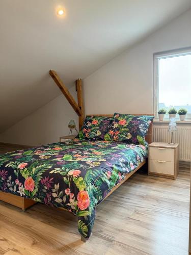 a bedroom with a bed with a floral bedspread at 120m2 APARTAMENT LAS I JEZIORO in Człuchów