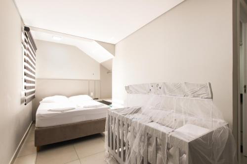 ein weißes Zimmer mit einem Bett und einem Fenster in der Unterkunft Lou Suítes - Suíte 02 - Conforto in Guarapuava