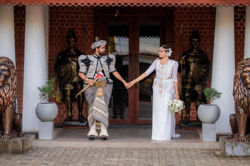 a bride and groom holding hands in front of a building at Golden stars hotel Dambulla in Dambulla