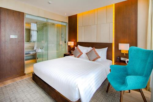 a bedroom with a bed and a blue chair at New Orient Hotel Da Nang in Da Nang