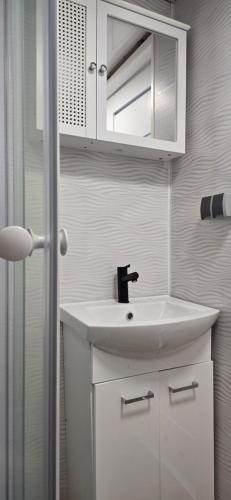 a white bathroom with a sink and a mirror at Domek nad jeziorem Romantyka in Giże