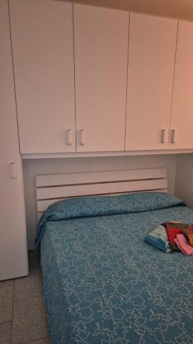 a bedroom with a bed with a blue comforter and white cabinets at PM 20 Via Paolo Dettori in Badesi