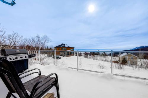 una parrilla en el balcón de una casa en la nieve en Le Haut-Perche - Spa and River View, en Petite-Rivière-Saint-François