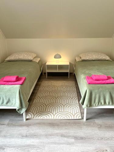 two beds in a room with pink towels and a table at Apartment Vainagu street Sigulda in Sigulda