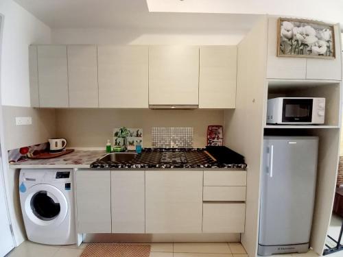 una cucina con mobili bianchi e un forno a piano cottura di Petal Homes at i-City - WiFi TV Box and 1 Carpark a Shah Alam