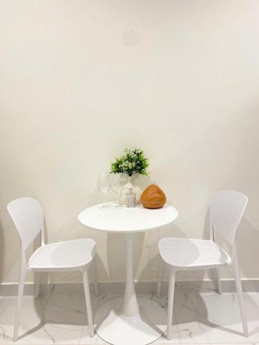 a white table with three chairs and a table with a vase of flowers at CĂN HỘ VINHOMES GRAND PARK QUẬN 9 Studio in Gò Công