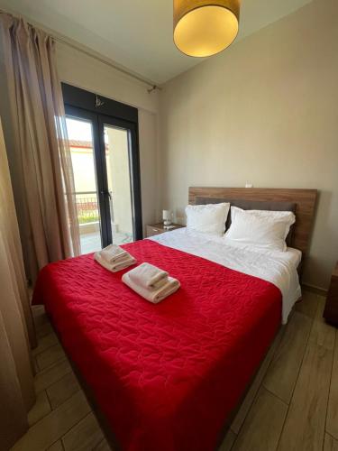 a bedroom with a red bed with two towels on it at Phaedra Residence in Nikiti