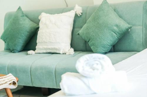 a blue couch with green pillows and a towel at CĂN HỘ VINHOMES GRAND PARK QUẬN 9 Studio in Gò Công