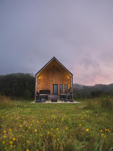 a small wooden cabin in a field of grass at NEW! Moonrise Meadow | Hot Tub | River | 360 Views in Stanton